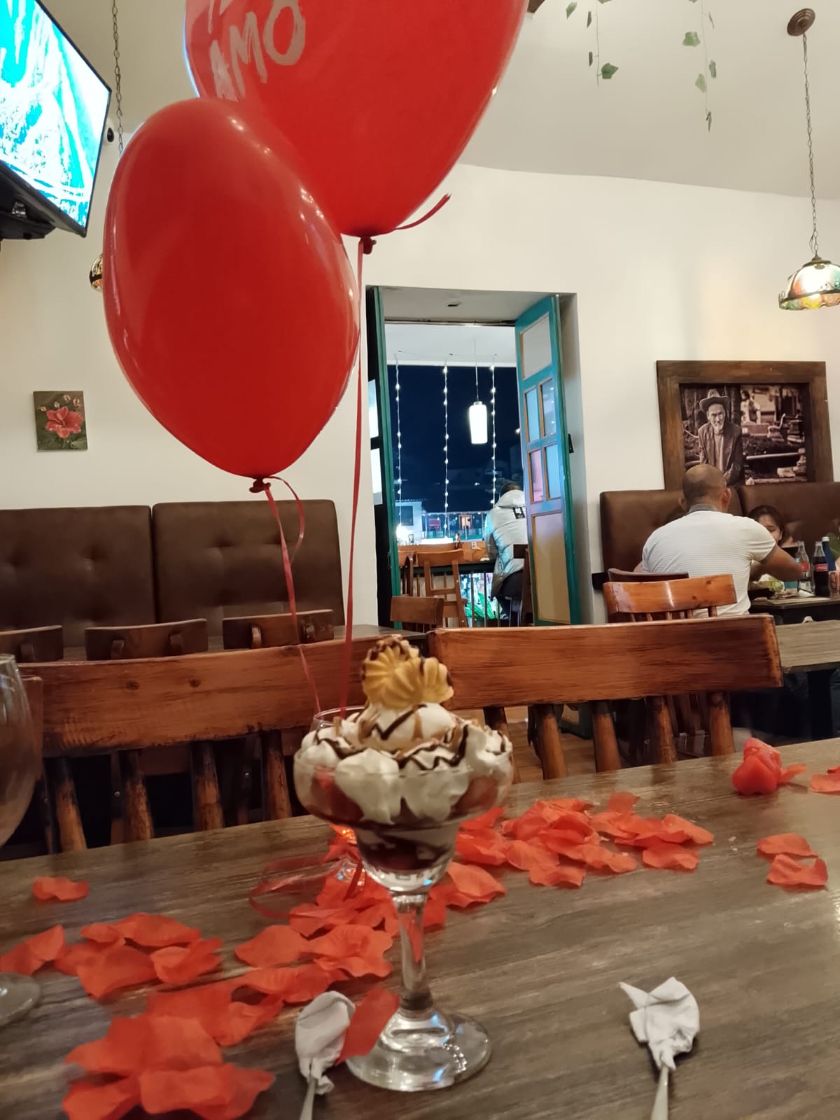 Copa de postre con globos de 'te amo' en el ambiente interior del restaurante en la noche